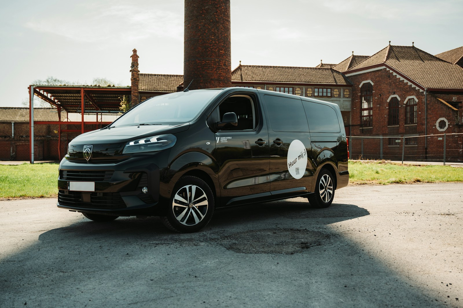 A black van parked outdoors near a brick building.